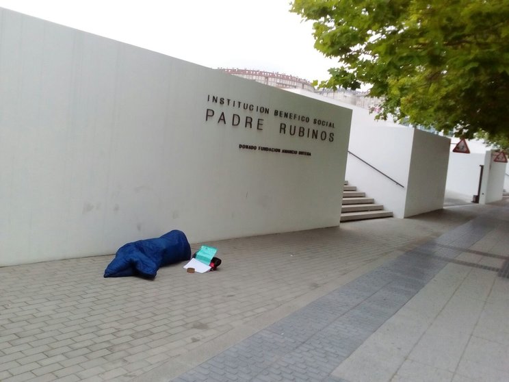Persoa sen recursos durmindo na rúa diante dunha institución benéfica da cidade