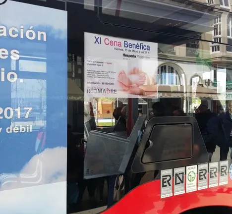 Cartel da actividade da entidade RedMadre colocado nunha das fiestras dus bus urbano